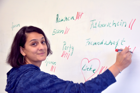 Navina De steht vor einem Whiteboard und notiert Begriffe wie Liebe, Freundschaft, Party oder Führerschein. Aspekte, die Jugendlichen wichtig sind.