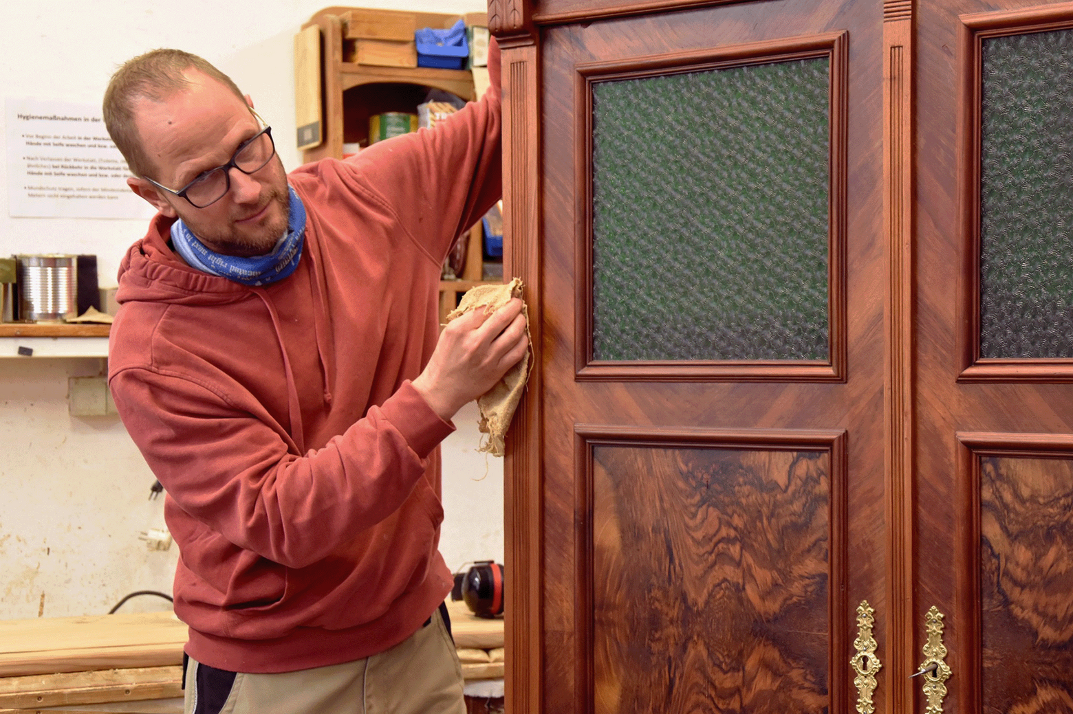 Schreinermeister Stefan Nothegger poliert einen alten Holzschrank.