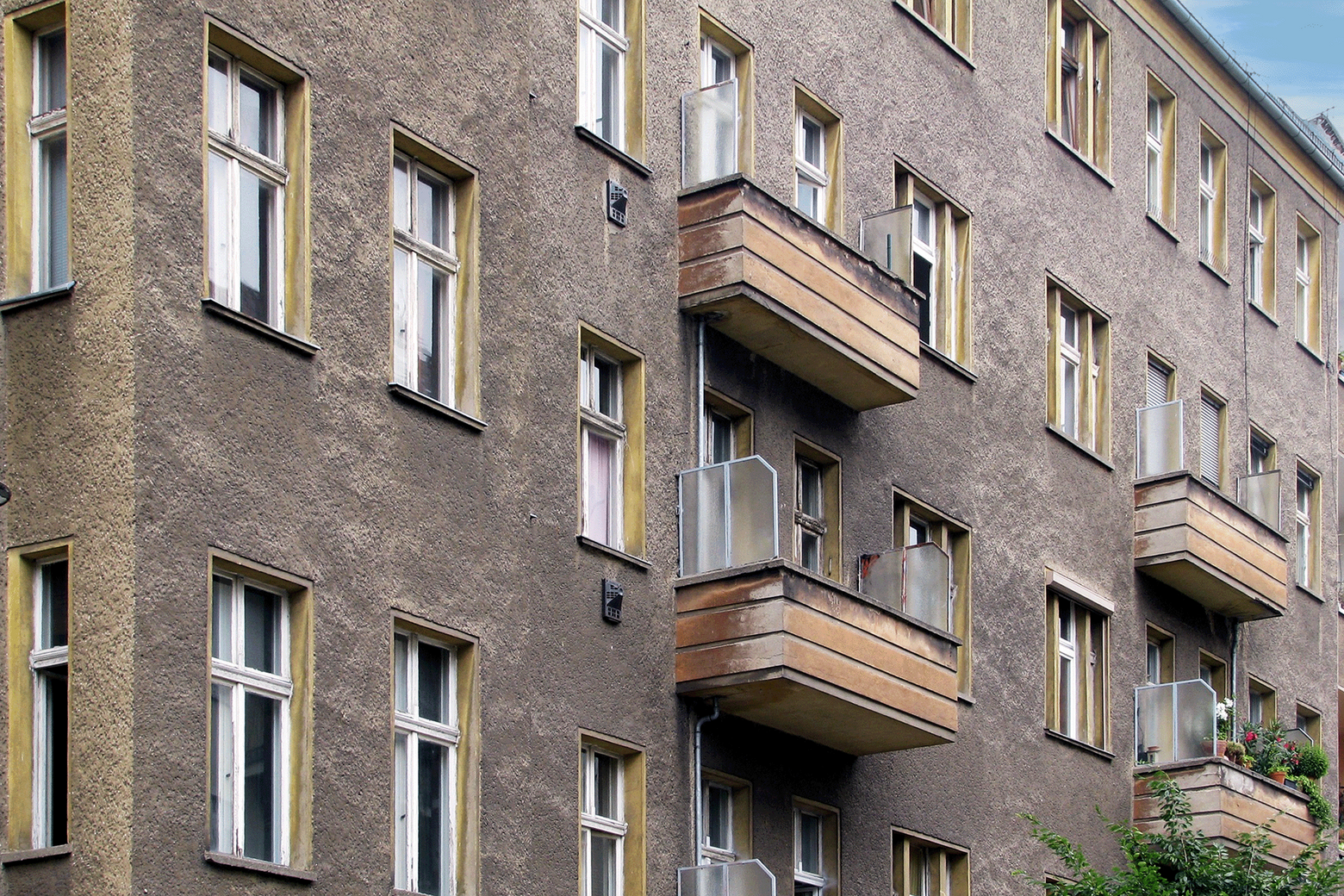 Blick auf eine Hausfassade mit mehreren Wohneinheiten über drei Stockwerke.
