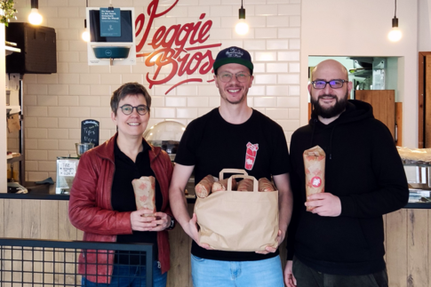 Nadia Fiedler, Steffen Jakel und Moritz Meier stehen vor der Theke im Veggie Bros und halten Wraps in den Händen.