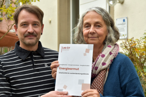 Robert Morfeld und Petra Müller halten gemeinsam ein Dokument zur Energiearmut in die Kamera.